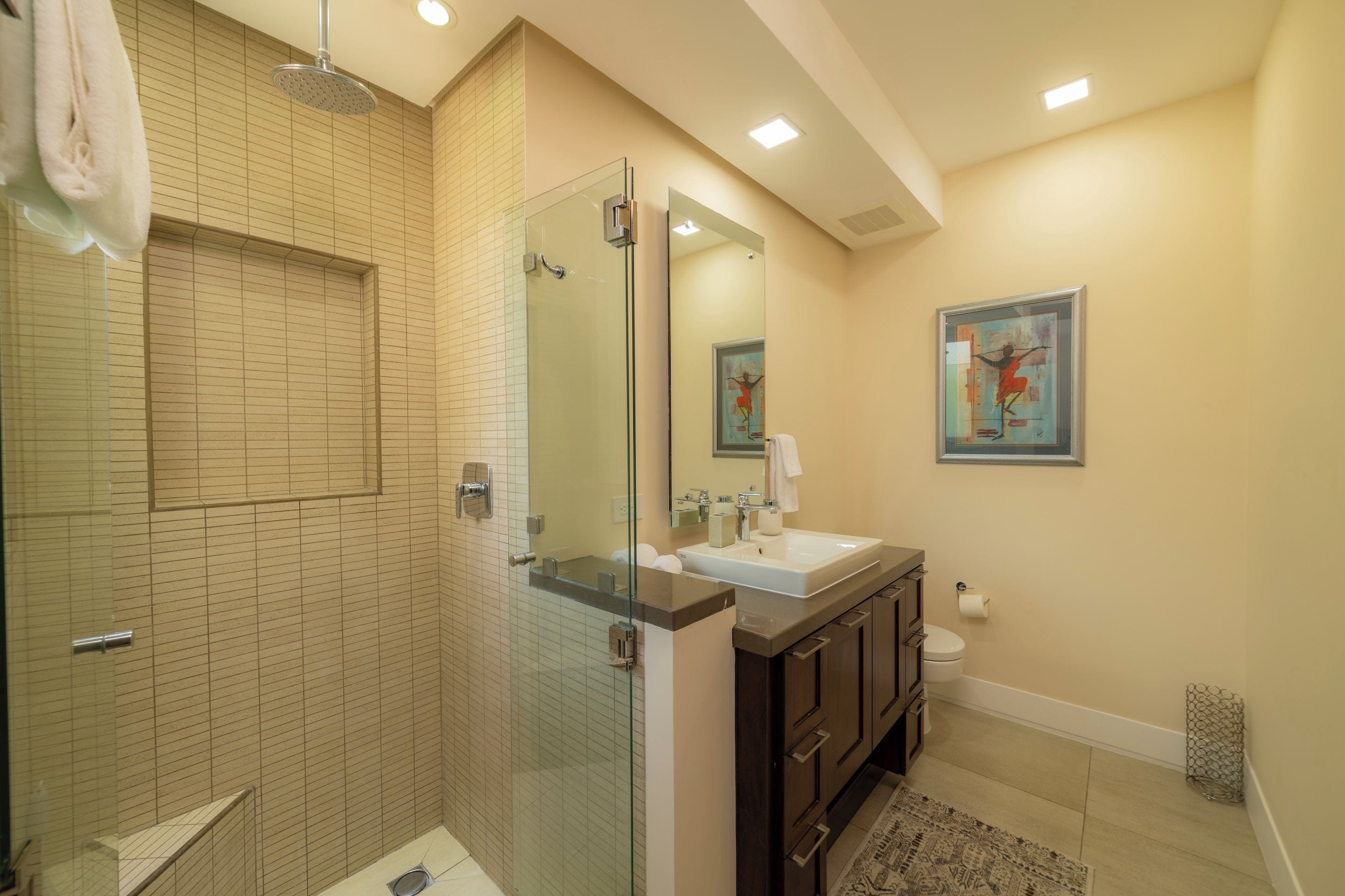 A modern bathroom with a glass shower enclosure, a sink with a mirror, and a toilet.