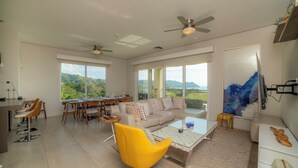 A spacious living area with a dining table, sofa, and yellow armchair. - Vista Los Suenos by Stay in Costa Rica (Jacó)