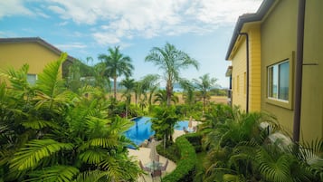 A resort with a swimming pool surrounded by lush greenery and palm trees.