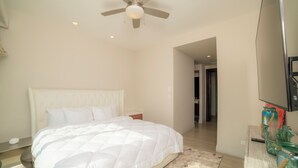 A bedroom with a bed, a ceiling fan, a nightstand, a mirror, and a decorative vase. - Vista Los Suenos by Stay in Costa Rica (Jacó)