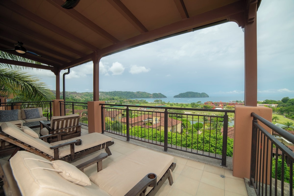 A covered outdoor seating area with a view of a coastal landscape.