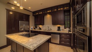 A modern kitchen with dark wood cabinets, stainless steel appliances, and a granite countertop. - Vista Los Suenos by Stay in Costa Rica (Jacó)