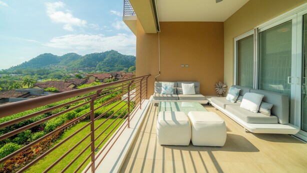 A balcony with a sofa, ottomans, and a dining table. - Vista Los Suenos by Stay in Costa Rica (Jacó)