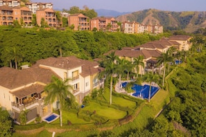 A residential area with multiple two-story houses, a swimming pool, and lush greenery. - Vista Los Suenos by Stay in Costa Rica (Jacó)
