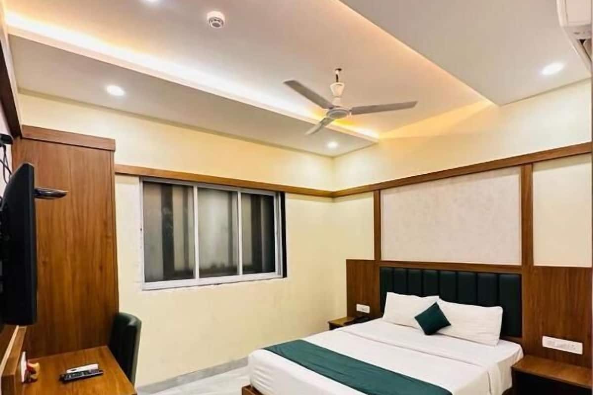 Quarto de hotel moderno com uma cama grande, uma escrivaninha, uma televisão e um ventilador de teto.