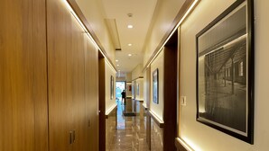 A hallway with wooden doors, framed pictures on the walls, and a polished marble floor. - Hotel Downtown-Near US Embassy (Mumbai)