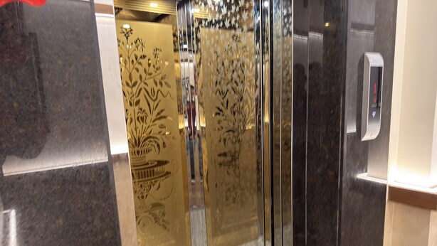 A modern elevator with reflective glass doors and a digital display. - Hotel Downtown-Near US Embassy (Mumbai)