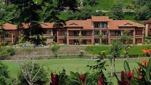 Ein mehrstöckiges Hotel mit einheitlichem Baustil, mit Balkonen und einem gepflegten Garten.