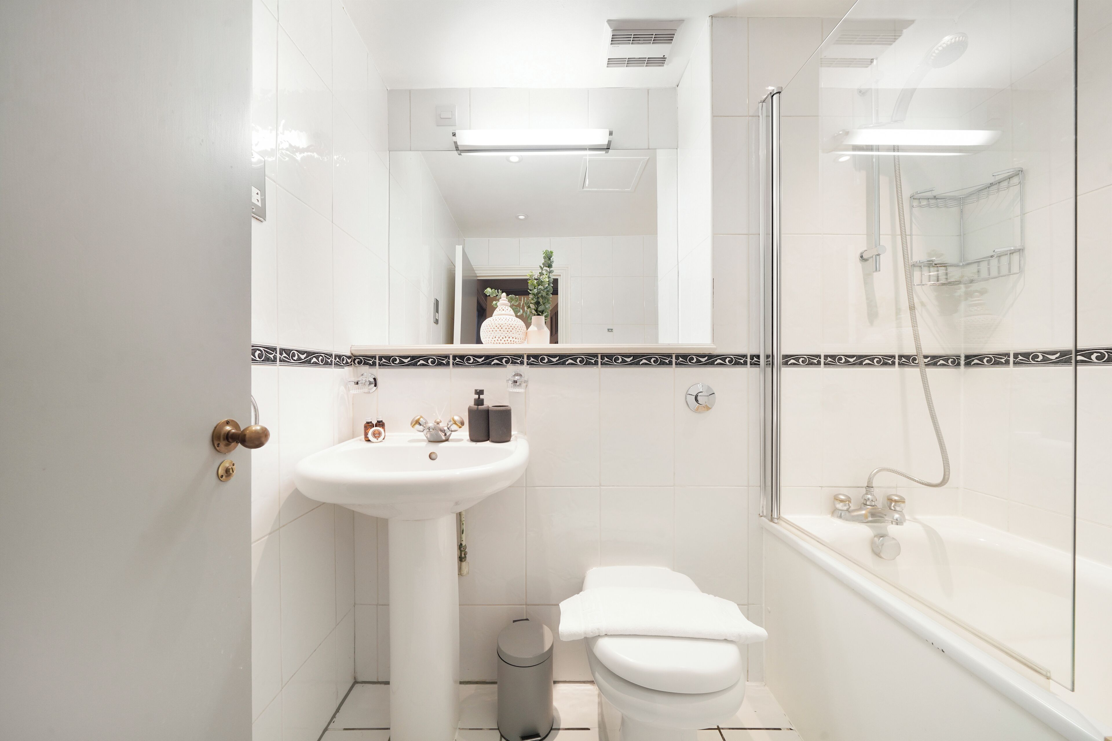 A modern bathroom with a white sink, toilet, and glass-enclosed shower.