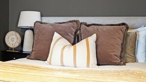 A neatly made bed with a striped pillow, a lamp, and a decorative plate on a nightstand. - Hertford Flat 7 (London)