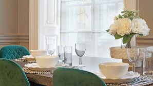 A dining table set with white bowls, glasses, and a vase with white flowers. - Hertford Flat 7 (London)