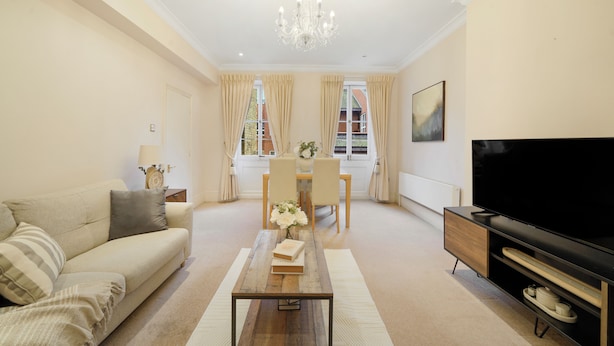 A living room with a sofa, coffee table, TV, and dining area. - Hertford Flat 8 (London)