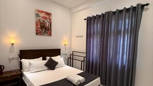 Una habitación de hotel con una cama, una mesita de noche, una lámpara, un cuadro en la pared y una cortina.