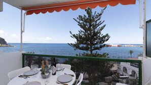 A dining table set for two with a view of the sea and a building in the background. - Ocean View 3 (Los Cristianos)
