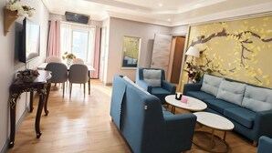 A modern living room with a blue sofa set, a coffee table, and a dining area with a table and chairs. - JUN YUE GRA Lagos hotel (Lagos)