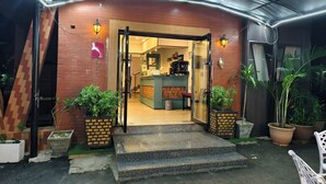 A building entrance with a brick facade, a glass door, and a small outdoor seating area with potted plants. - JUN YUE GRA Lagos hotel (Lagos)