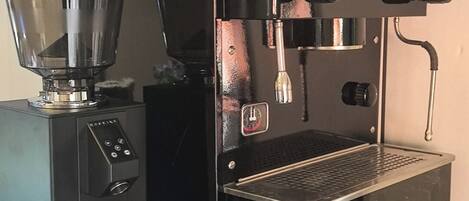 A black espresso machine with a digital display, a portafilter, and a drip tray on a teal counter.
