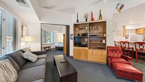 Una sala de estar moderna con un sofá, un televisor, un mueble de madera y un sillón reclinable rojo.