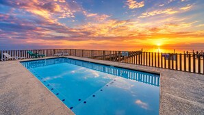 Ein Schwimmbecken mit Sonnenuntergangsblick, ein Holzzaun und ein Schild, das das Einbringen von Glas verbietet.