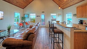 Eine geräumige Küche mit Holzbalkendecke, eine Essecke mit Glastisch und ein Wohnbereich mit Ledersofa.