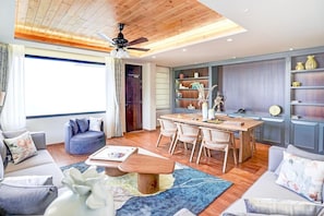 A modern living room with a dining area, wooden ceiling, and built-in shelving.