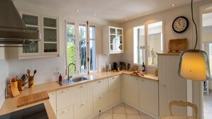 Eine moderne Küche mit weißen Schränken, einer Holz Arbeitsplatte, einem Spülbecken und einem Essbereich mit Tisch und Stühlen.