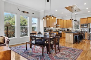 A spacious kitchen with wooden cabinets, a central island, and pendant lighting. - Modern Home + Firepit + Balcony + Near East Austin | Chestnut Ember by AvantStay (Austin)