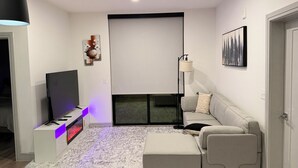 Una sala de estar moderna con una televisión de pantalla plana, un sofá, una mesa de centro y una chimenea.