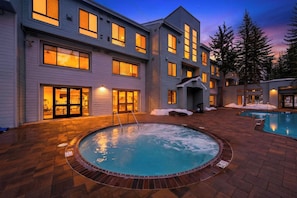 A multi-story building with a swimming pool, outdoor lighting, and snow on the ground. - Ski-In/Ski-Out Condo • Pool, Hot Tub Access • Steps to KT-22 | The Traverse (Olympic Valley)