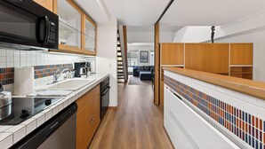 Une cuisine moderne avec des meubles en bois, un micro-ondes noir et un pare-feu en carreaux.