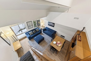 Ein geräumiger Wohnbereich mit einem blauen Sofa, einem Holzesstisch mit einer Teller voller Speisen und einer Treppe, die zu einer oberen Etage führt.
