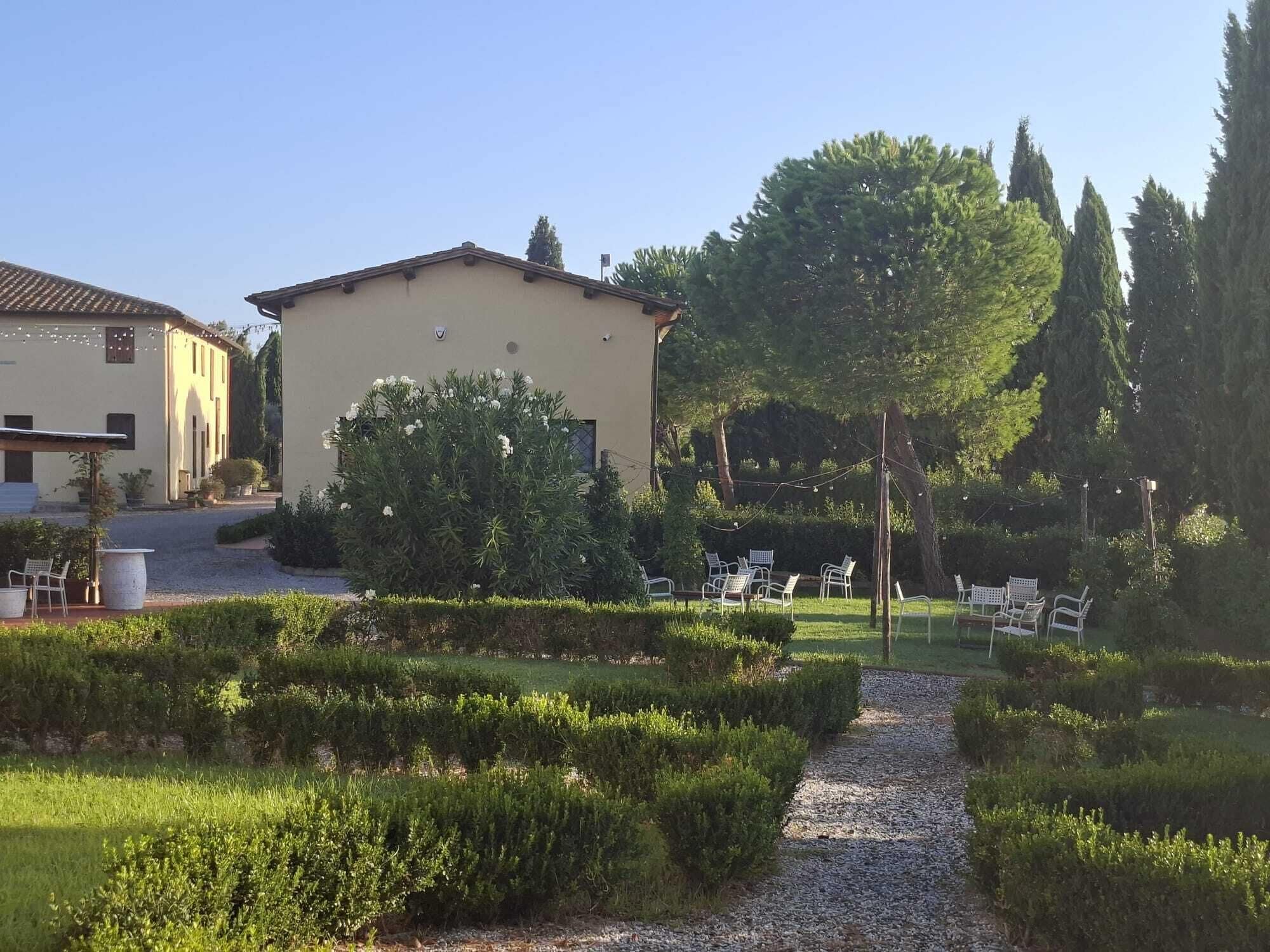 A garden with a gravel path, neatly trimmed hedges, and outdoor seating.