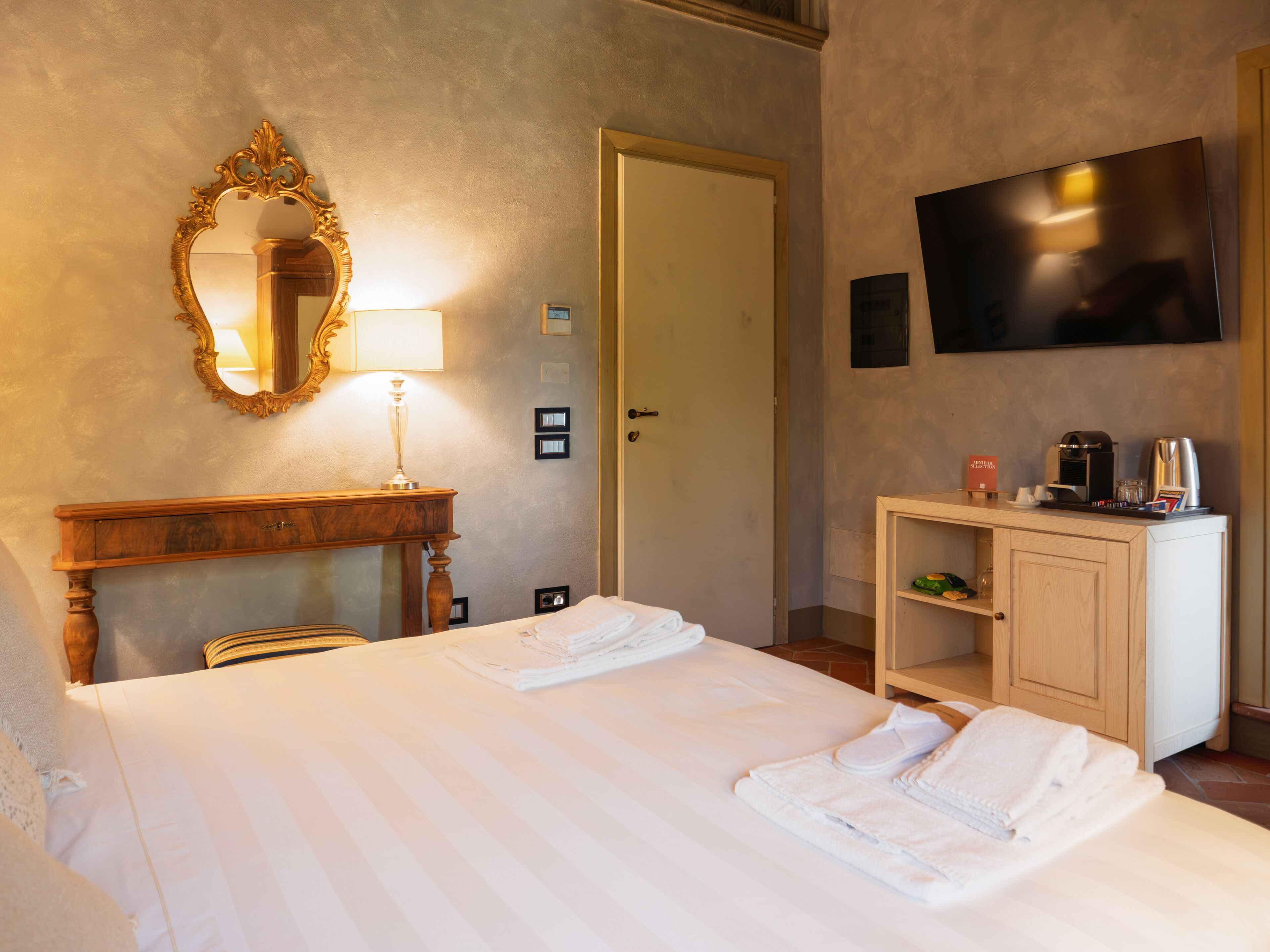 Une chambre d’hôtel équipée d’un lit, d’un bureau avec une lampe, d’une télévision et d’un mini-bar.