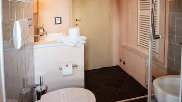 Une salle de bain comprenant des toilettes, un bidet et un espace douche.