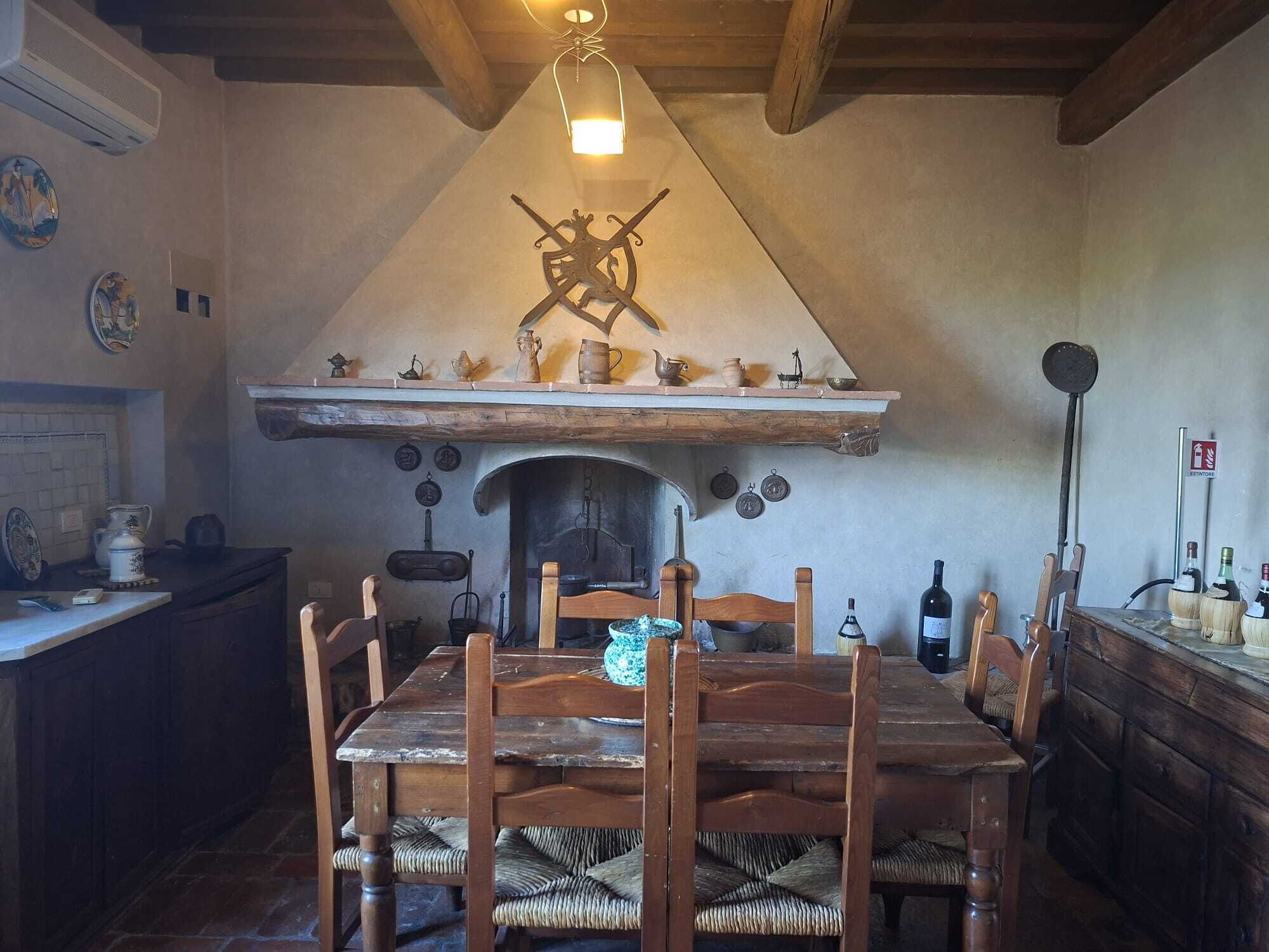 A rustic dining area with a wooden table, chairs, and a fireplace.