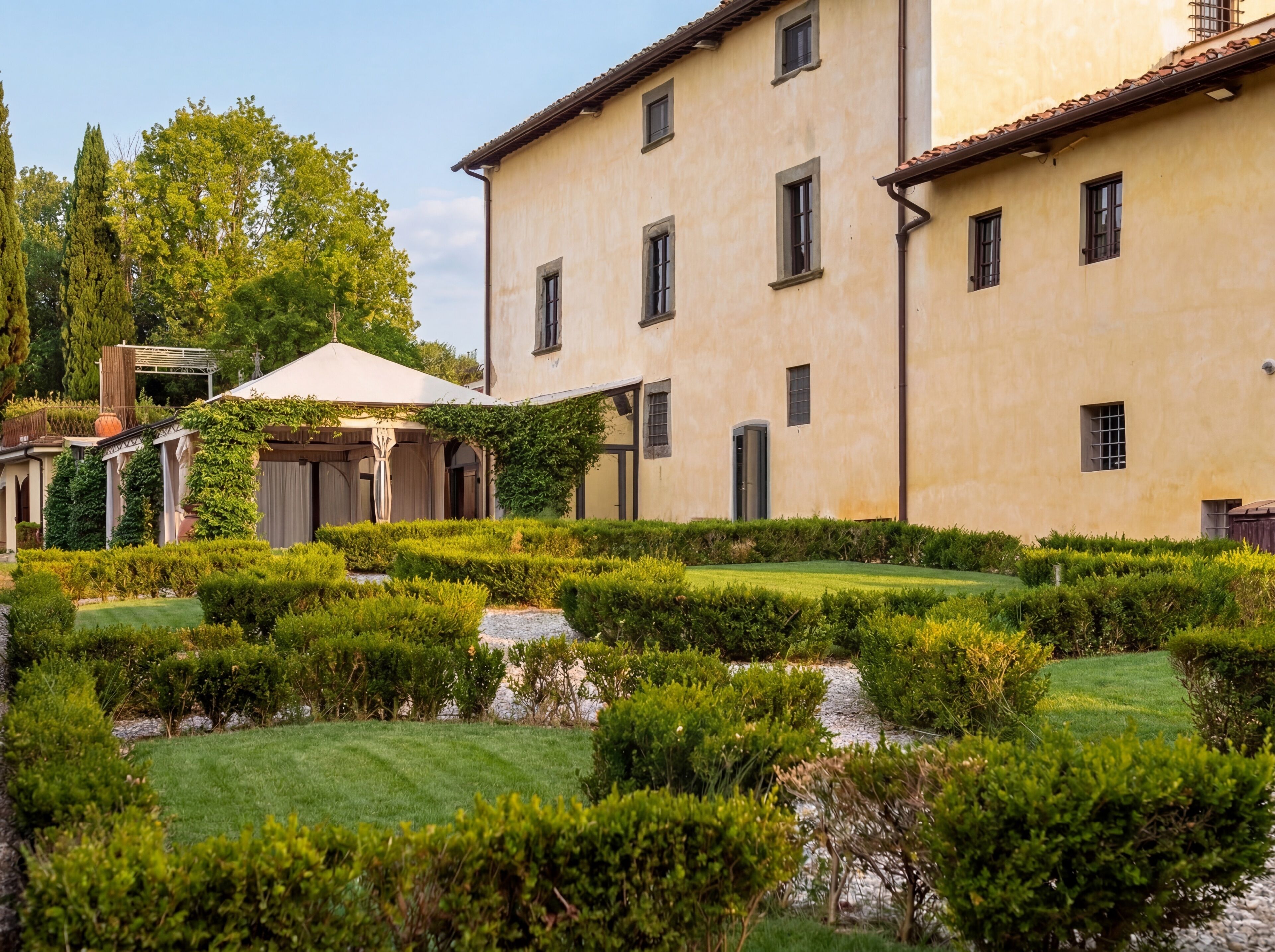 Un edificio con patio, pérgola y jardín bien cuidado.