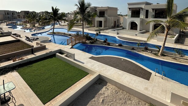 Ein Resort mit mehreren Schwimmbecken, Palmen und modernen Gebäuden.