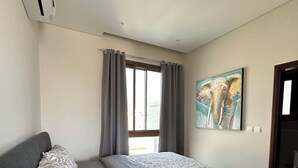 Ein Schlafzimmer mit einem Bett, grauen Vorhängen, einem Fenster und einem Wandbild.