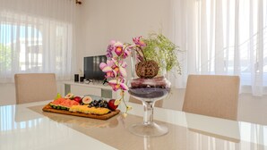 Taula de menjador amb un plat de fruita, un vas amb flors i un got decoratiu.