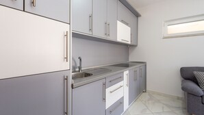 Una cocina moderna con armarios grises, un lavamanos de acero inoxidable y un sofá gris.