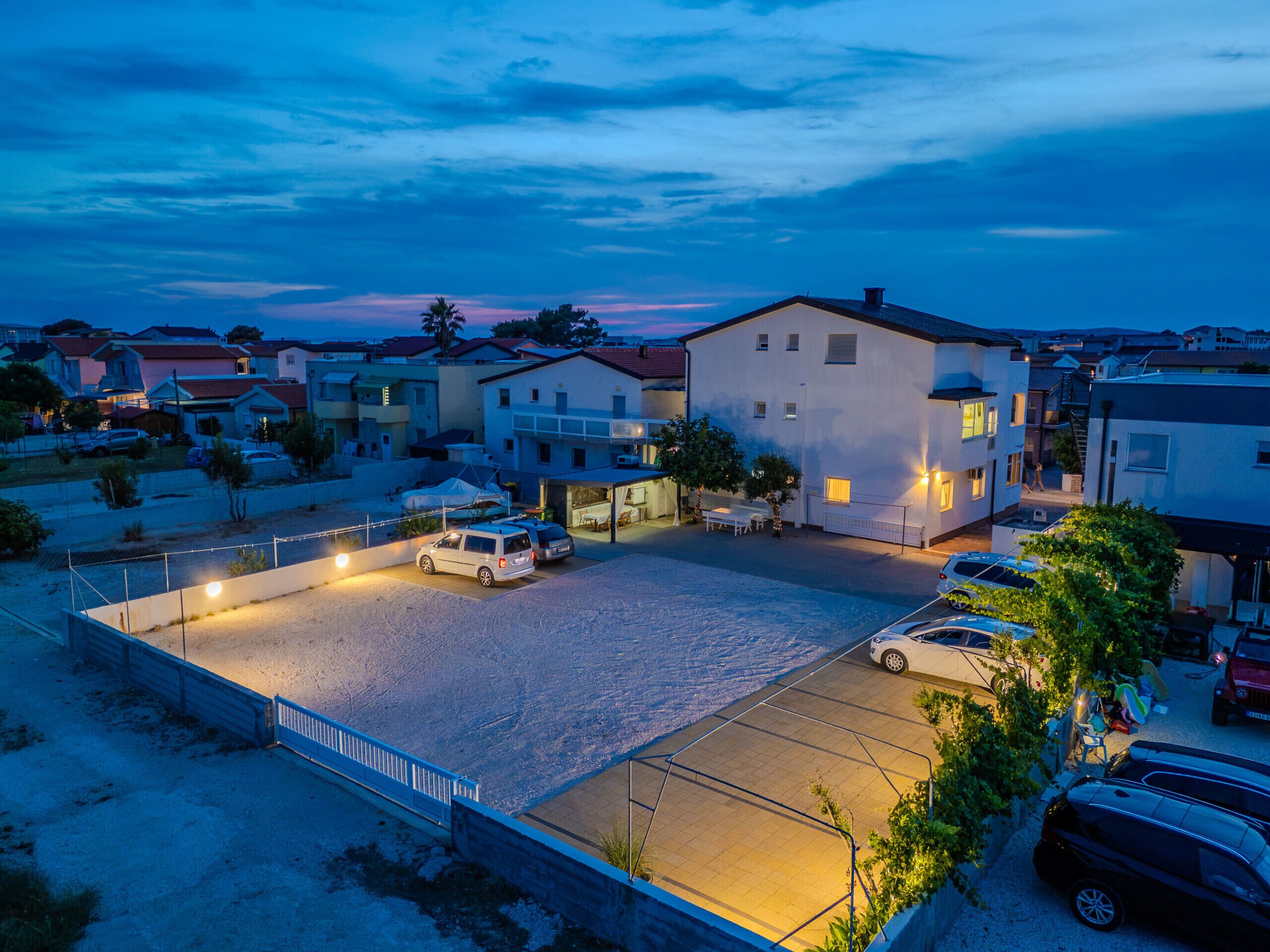 A residential area with houses, a paved parking lot, and a clear sky.