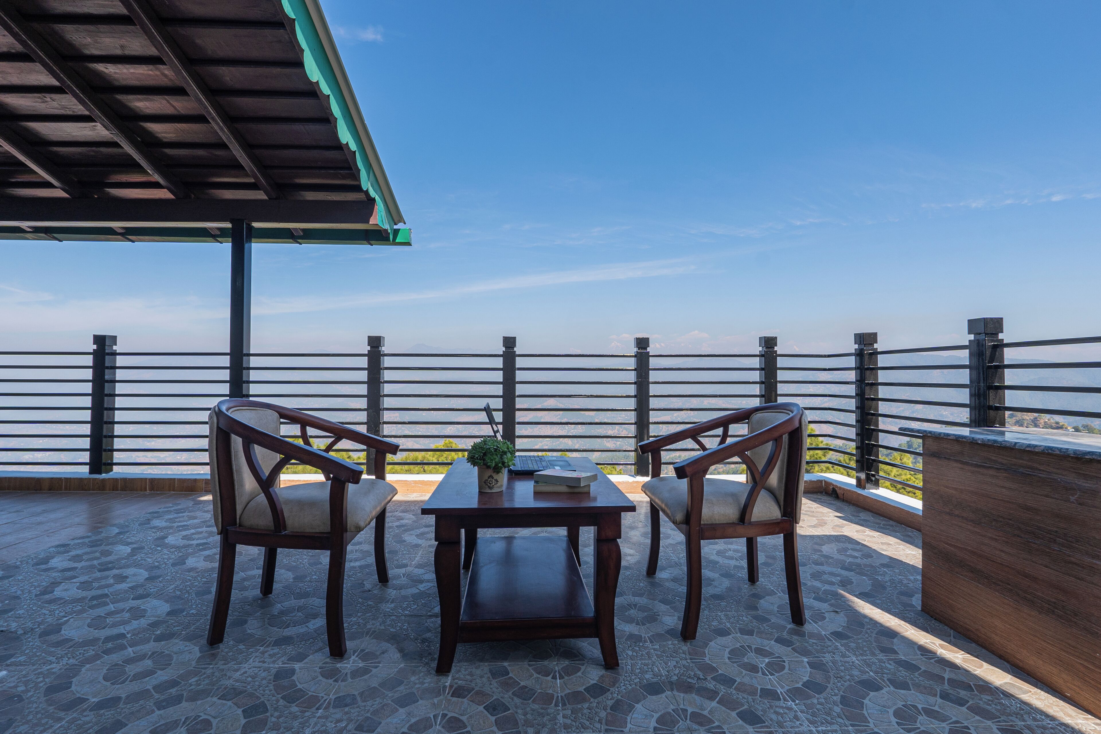 A terrace with a table and two chairs, a potted plant, and a view of the sea.