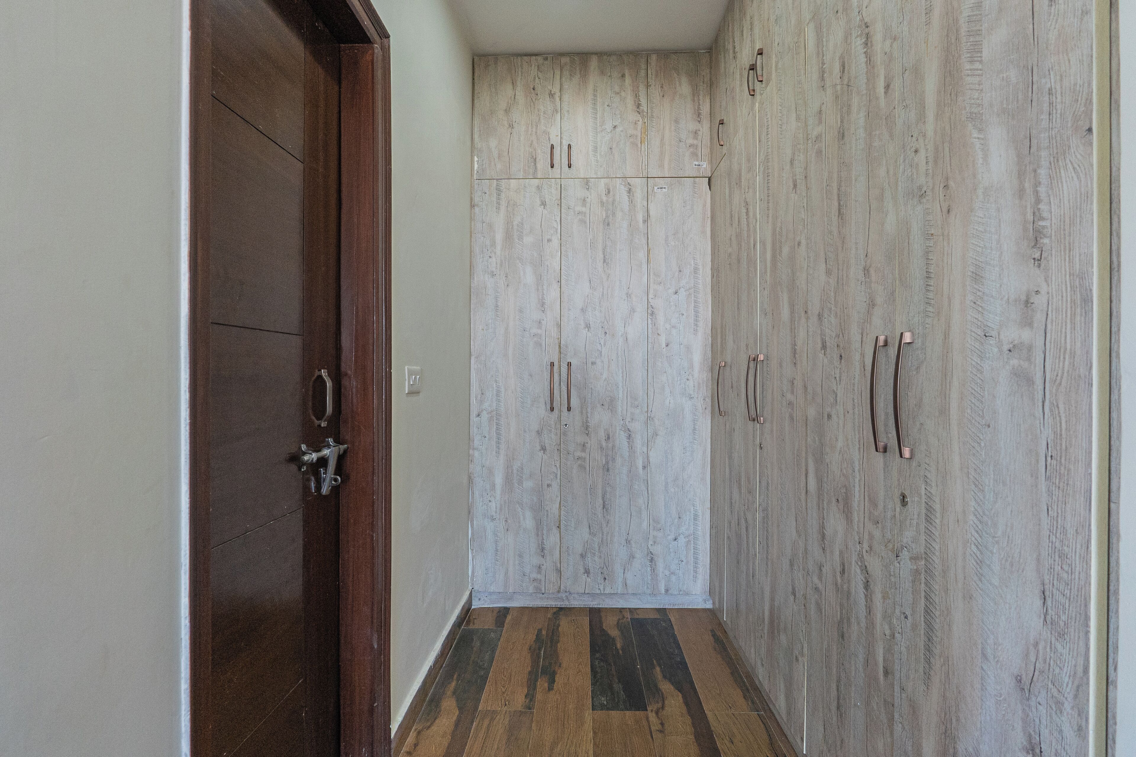 A hallway with wooden flooring and a wardrobe with multiple doors.