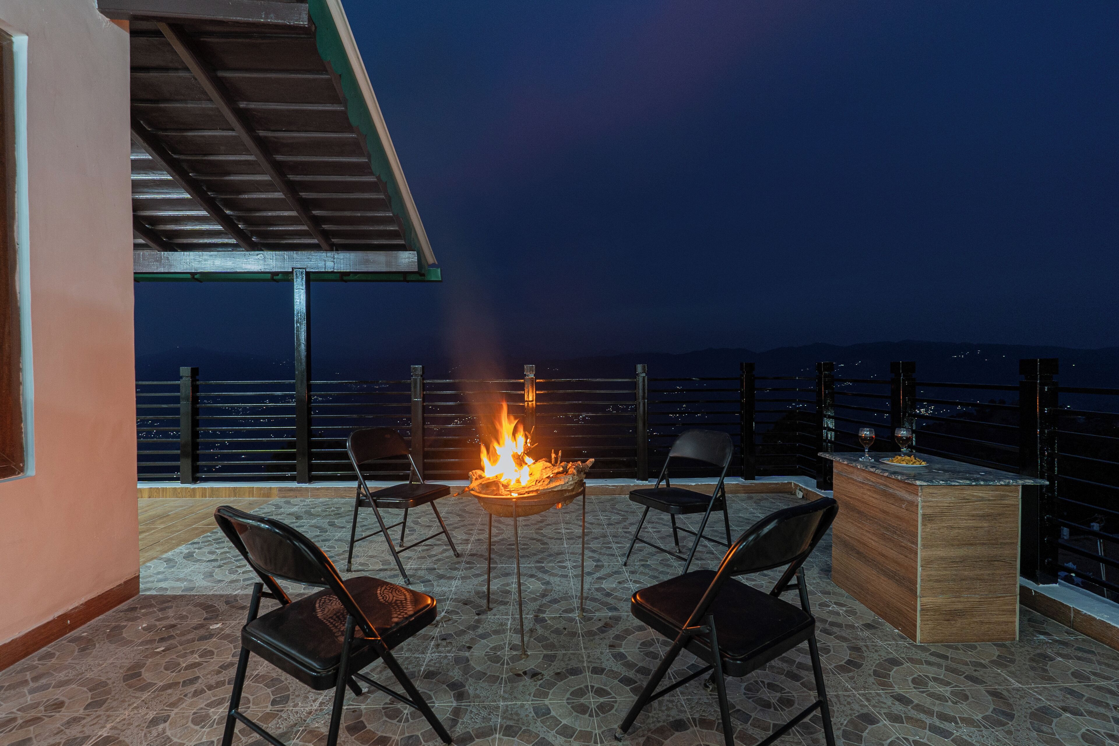 A terrace with a fire pit, four chairs, and a bar area.