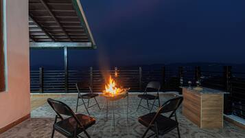 A terrace with a fire pit, four chairs, and a bar area.