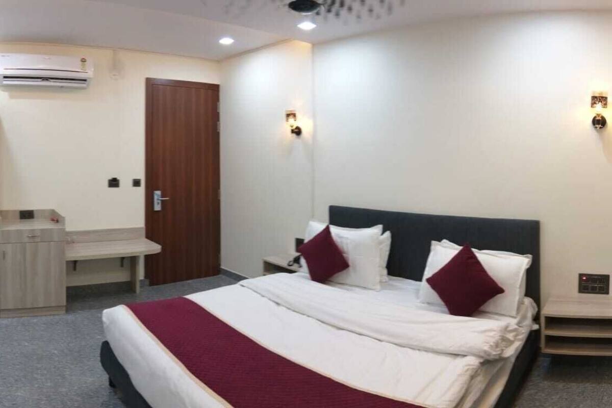 Une chambre d’hôtel comprenant un lit, des tables de chevet, un bureau, un climatiseur et une armoire.