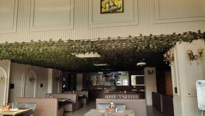 Ein Restaurant mit Sitzecken und Tischen, einer Bar und einer dekorativen Decke.