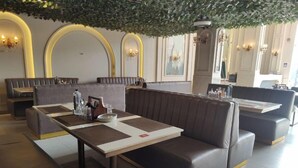 Ein modernes Restaurant mit Ledersitzen und einem zentralen Tisch, ausgestattet mit einem Dachgarten und eleganten Wandleuchtern.