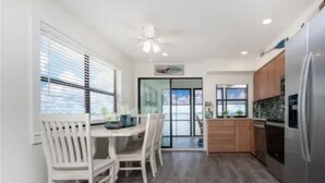 A modern kitchen with a dining area, wooden cabinets, and a stainless steel refrigerator.