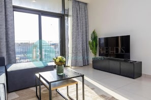 A modern living room with a large window, a sofa, a coffee table, a TV, and a cabinet. - Bloomfields Classic 1Bedroom In Park (Dubai)